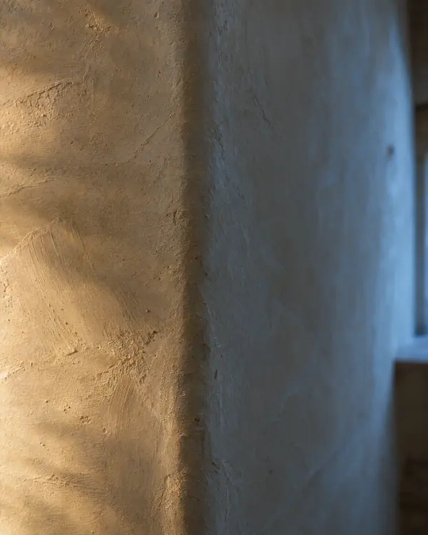 Pared de estuco de cal con las pasadas de la llana a contraluz