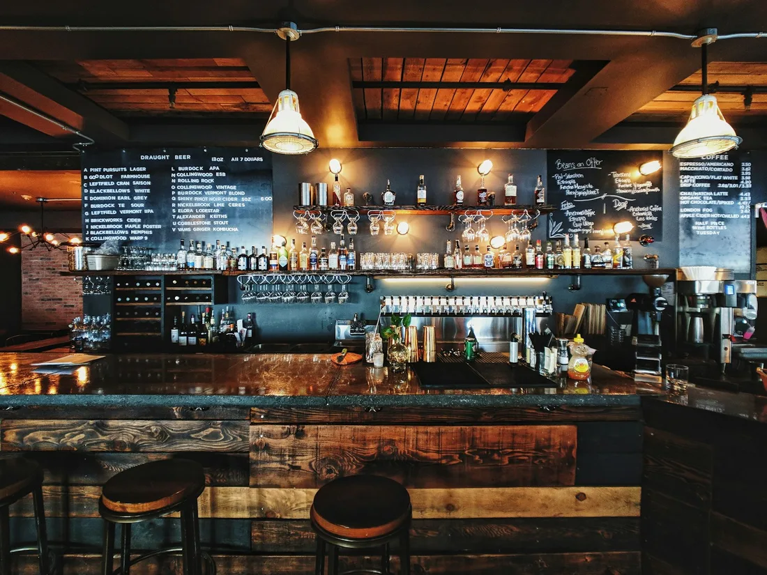 La barra cálida de un bistró, con lámparas bajas y taburetes de madera