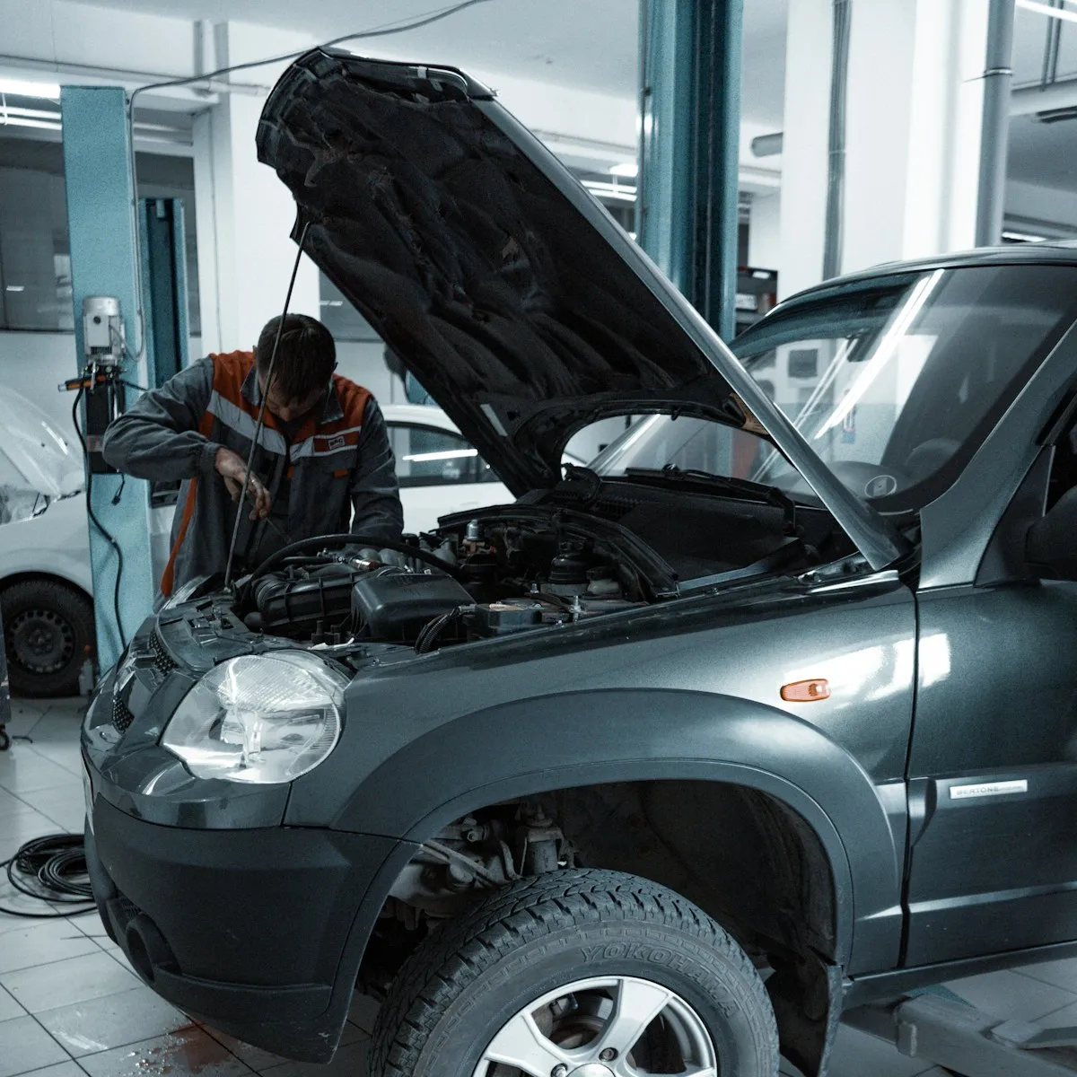 Profesional revisando el motor de un vehículo con el capó abierto en un taller