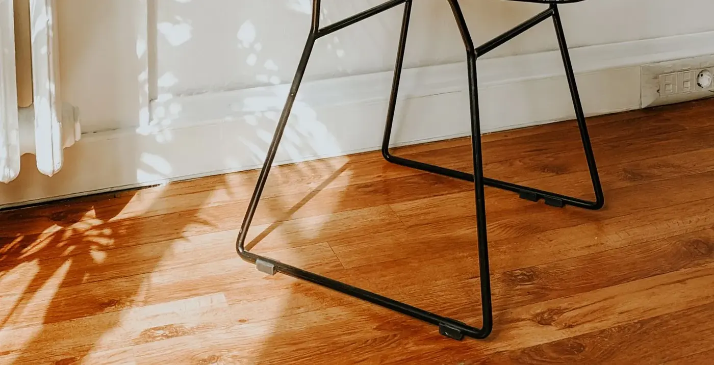 Luz de la tarde sobre un suelo de madera junto a la pata de una silla